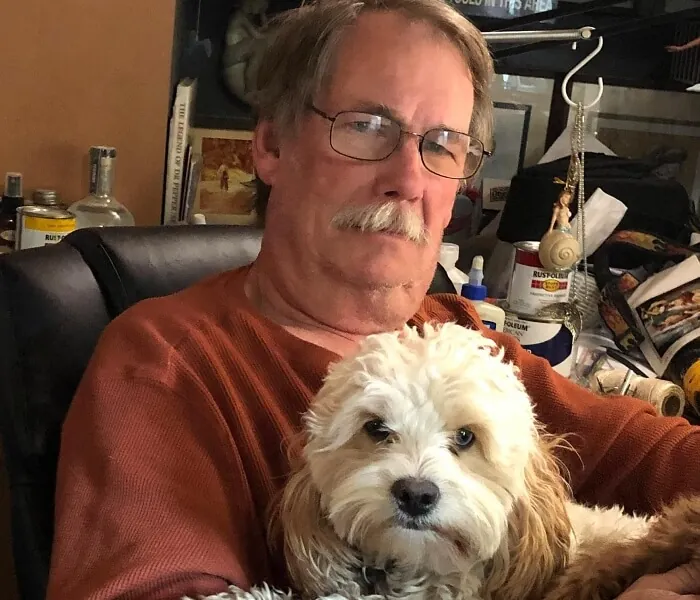 Wally Stewart holding a white and brown cockapoo dog